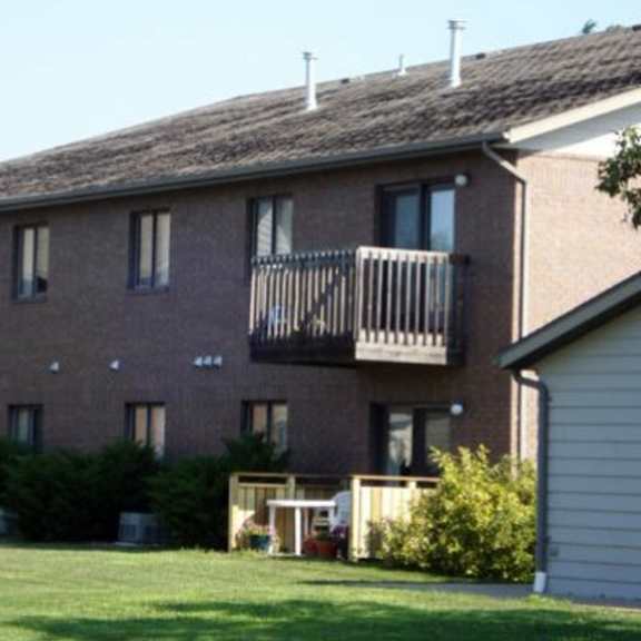 a brick building with a balcony and a small garden in front.