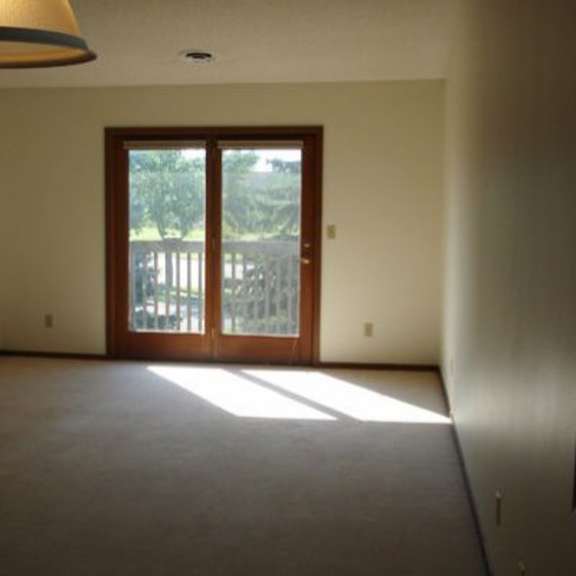 a room with a brown carpet and a brown door leading outside.