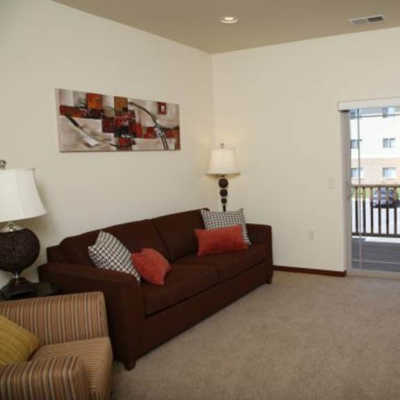 a living room with a brown couch and a painting on the wall.