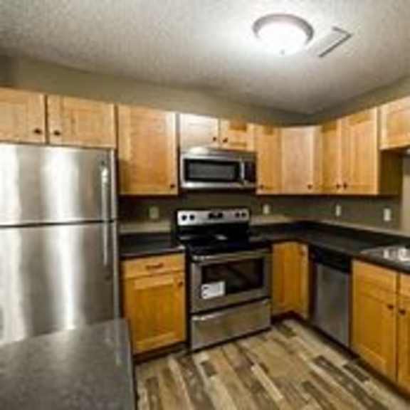 a kitchen with wooden cabinets and a stainless steel refrigerator.