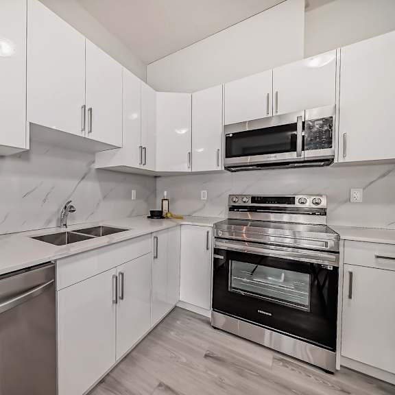 an all white kitchen with stainless steel appliances and white cabinets