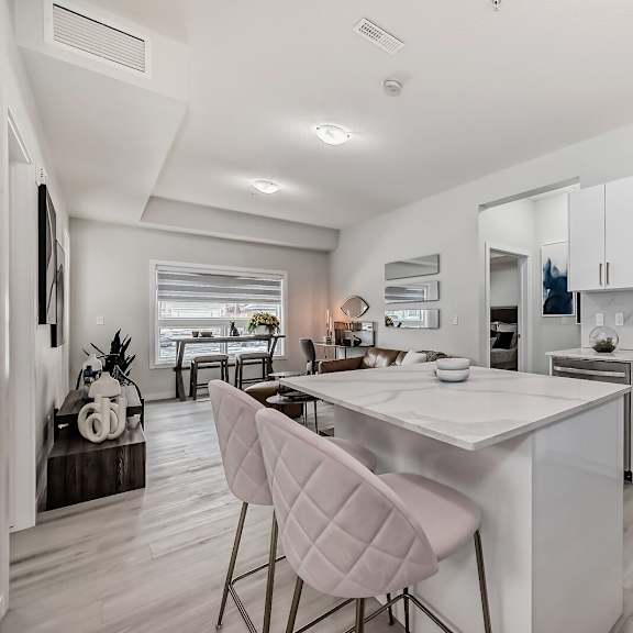 an open kitchen with white cabinets and a marble counter top