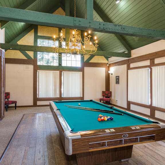 a pool table in a room with wooden floors and a chandelier.
