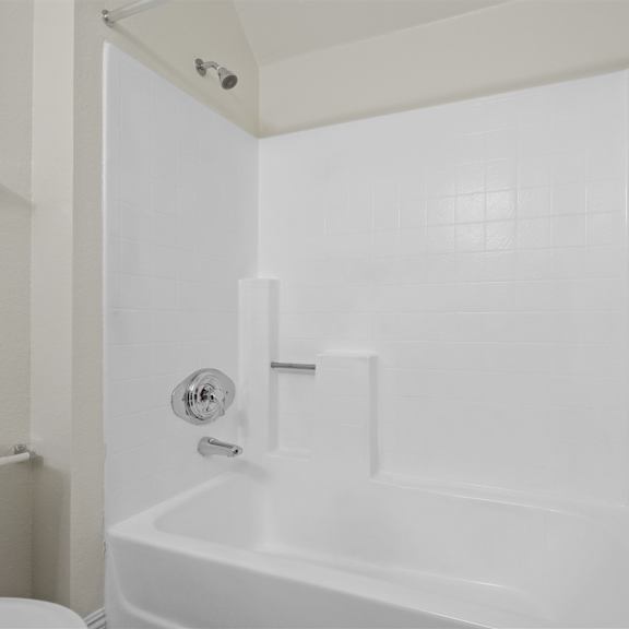 a white bathroom with a toilet, tub, and shower.