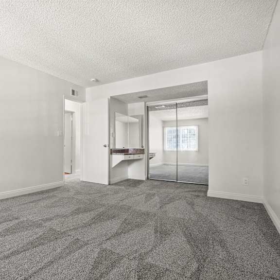 a room with a carpeted floor and a glass door leading to a balcony.