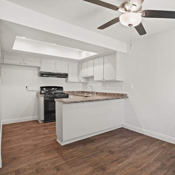 a kitchen with a wood floor and a ceiling fan.