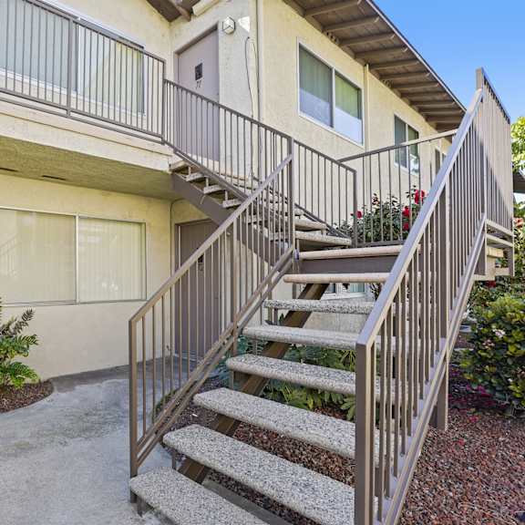 a building with a grey door and a staircase leading to the second floor.