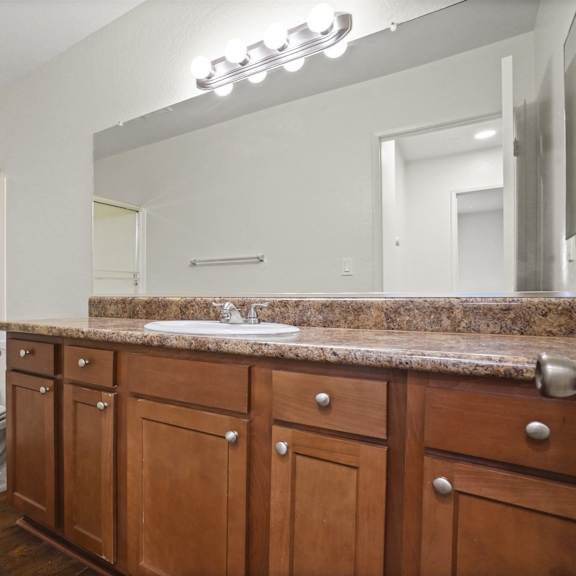 a bathroom with a toilet, sink, and wooden cabinets.
