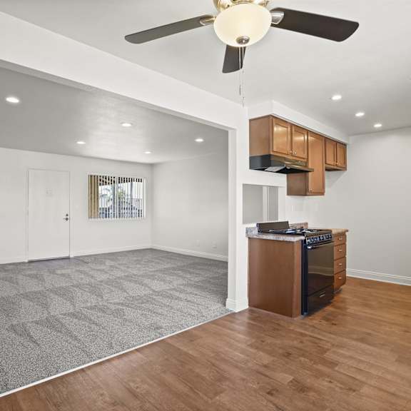 a spacious kitchen with a ceiling fan and wooden floors.
