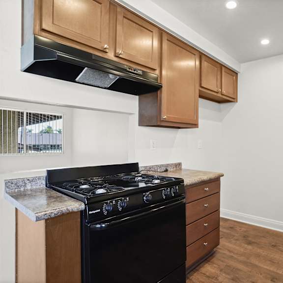 a kitchen with a black stove top oven and wooden cabinets.