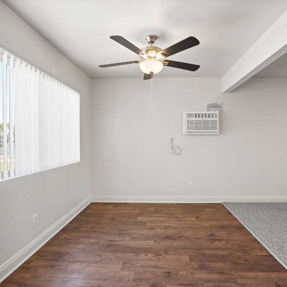 a room with a ceiling fan and a window with blinds.