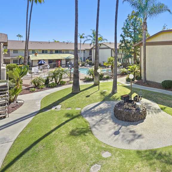 a courtyard with a fountain surrounded by palm trees.