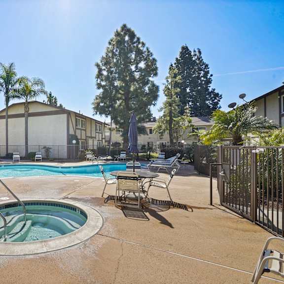 a pool surrounded by chairs and trees.