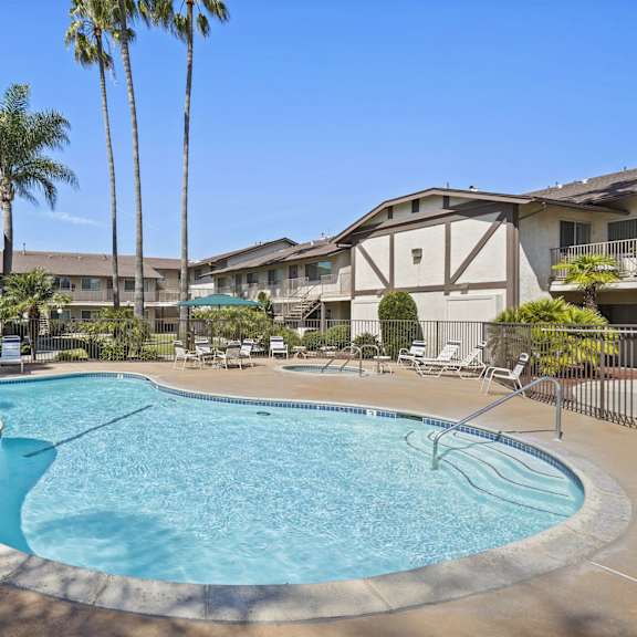 a swimming pool surrounded by palm trees and lounge chairs.
