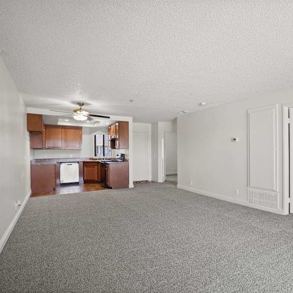 a spacious living room with a kitchen in the background.