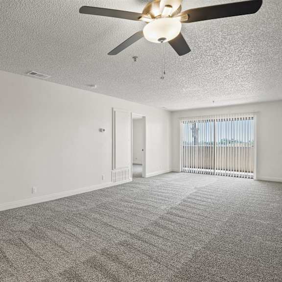 a spacious room with a ceiling fan and carpeted floor.
