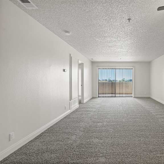 a spacious room with a ceiling fan and carpeted floor.