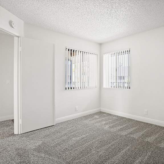 a room with a carpeted floor and two windows.