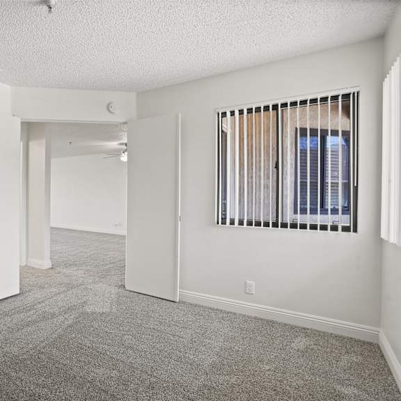 a spacious room with a carpeted floor and a window with blinds.