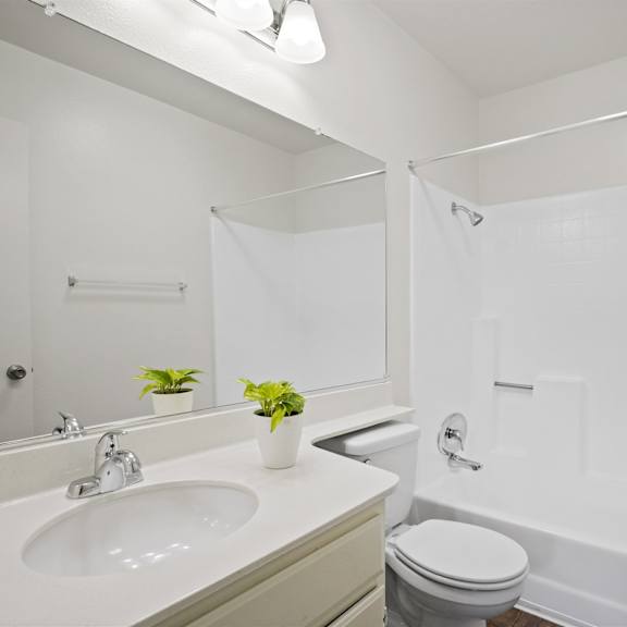 a white bathroom with a toilet, sink, and bathtub.