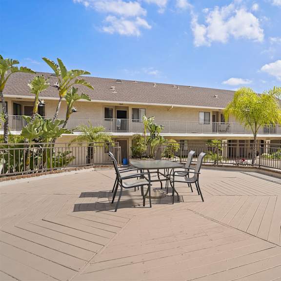 a patio with a table and chairs is surrounded by a metal fence.