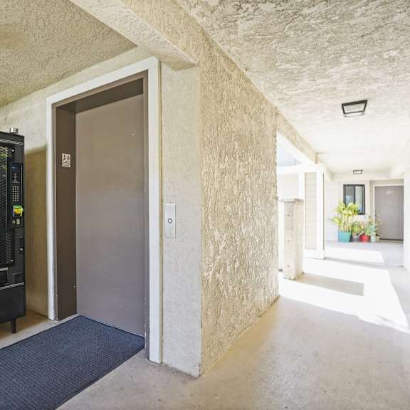 a vending machine is in a hallway with a door to the right.