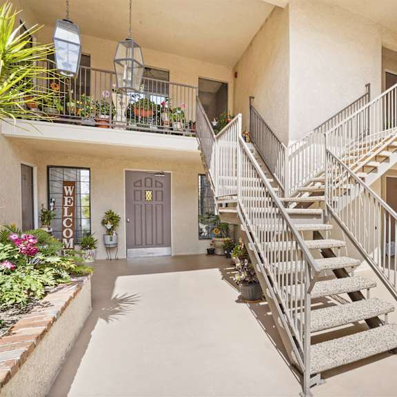 a staircase with a metal railing leads to a balcony with plants on it.