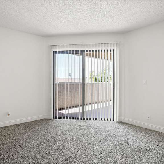 a room with a carpeted floor and a sliding glass door.