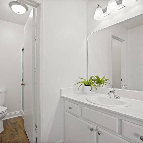 a white bathroom with a toilet, sink, and mirror.