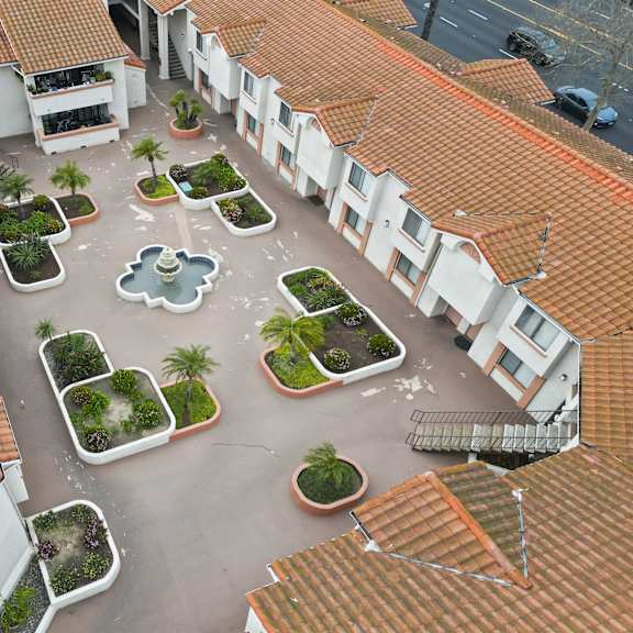 a courtyard surrounded by buildings with a fountain in the middle.