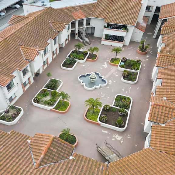 a courtyard surrounded by buildings with a fountain in the middle.