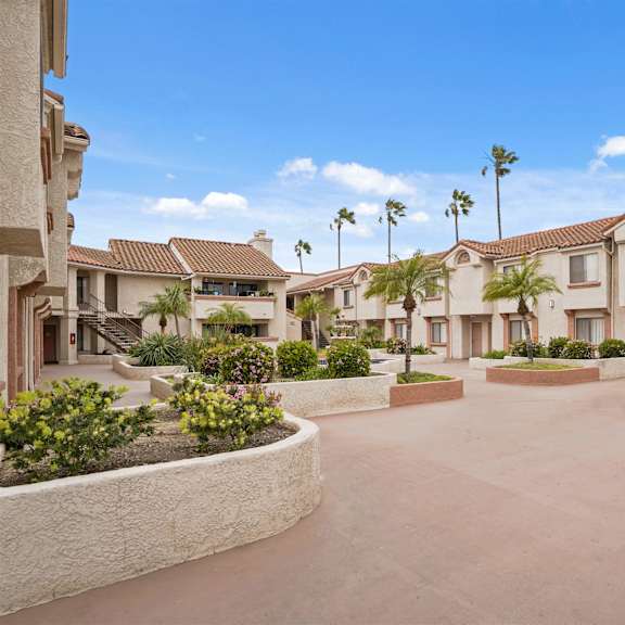 a sunny day at a residential complex with houses and palm trees.