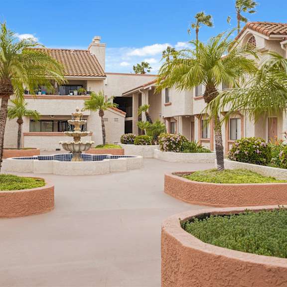 a large house with a courtyard and palm trees.
