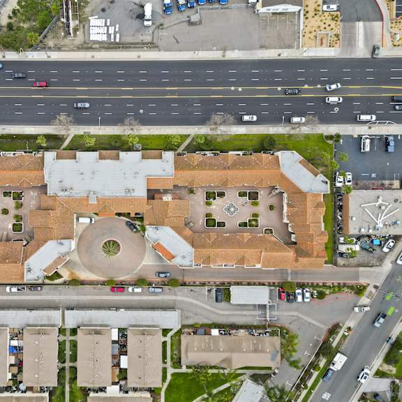 a large building with a circular courtyard in the middle is surrounded by smaller buildings and a busy road.