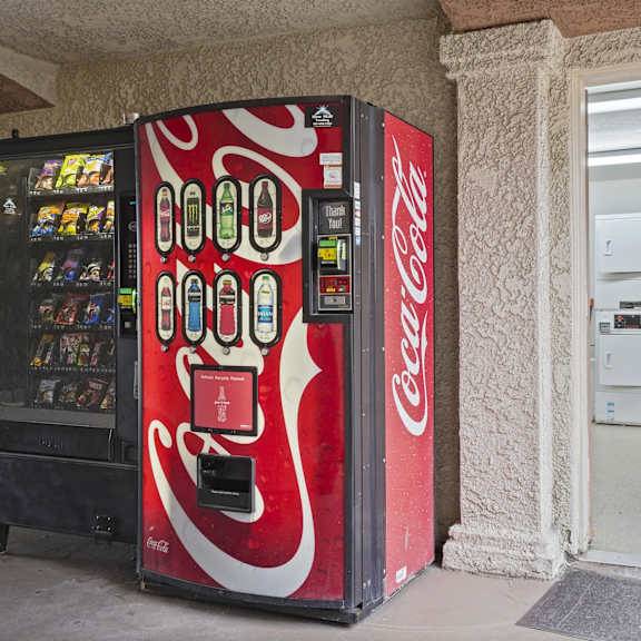 a coca-cola vending machine sits next to a white door.