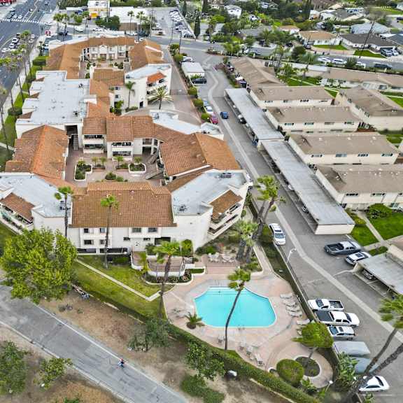 a bird's eye view of a residential area with a swimming pool and a road running through it.
