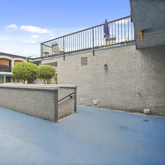 a courtyard with a concrete floor and a small tree in a planter.