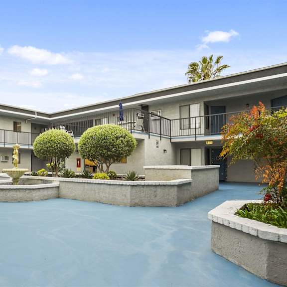 a courtyard with a fountain and trees in front of a building.