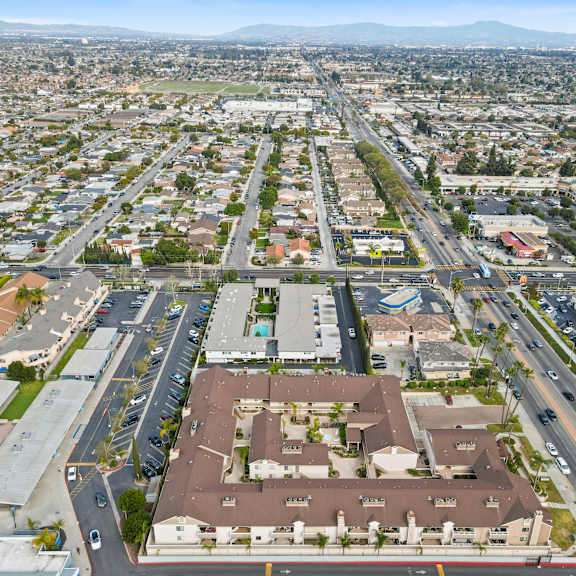 a large, open parking lot is surrounded by apartment buildings and a busy road.
