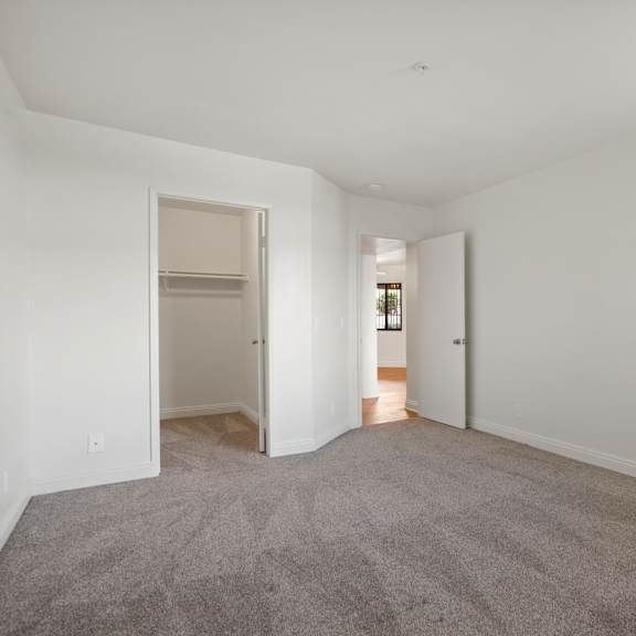 a spacious empty room with carpeted floor and white walls.