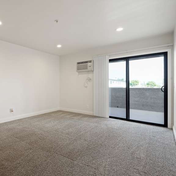 a room with a carpeted floor and a sliding glass door.