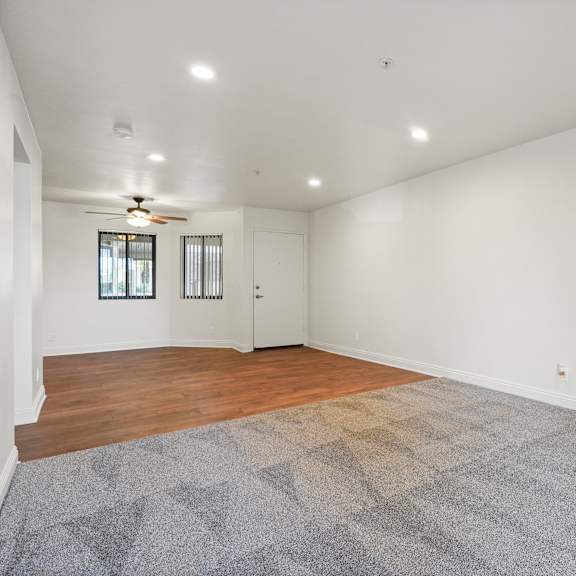 a room with a ceiling fan and a rug on the floor.