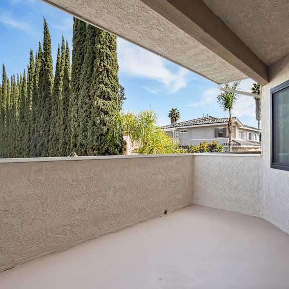 a patio with a white wall and a window overlooking a residential area.