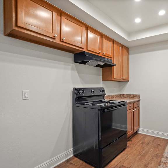 a kitchen with a black stove top oven and wooden cabinets.
