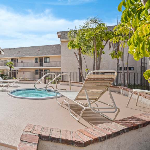a pool with a hot tub and chairs in front of a house.