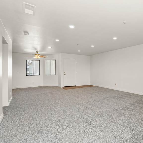a spacious room with a carpeted floor and a ceiling fan.