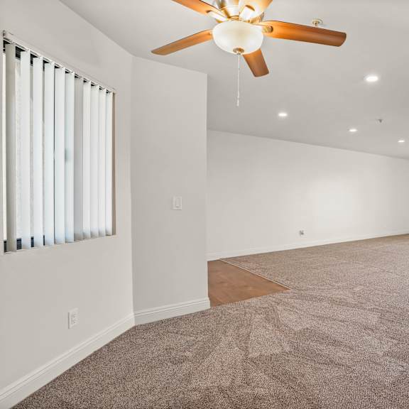 a spacious room with a ceiling fan and carpeted floor.