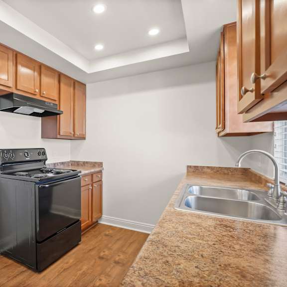 a modern kitchen with wooden cabinets and a black dishwasher.