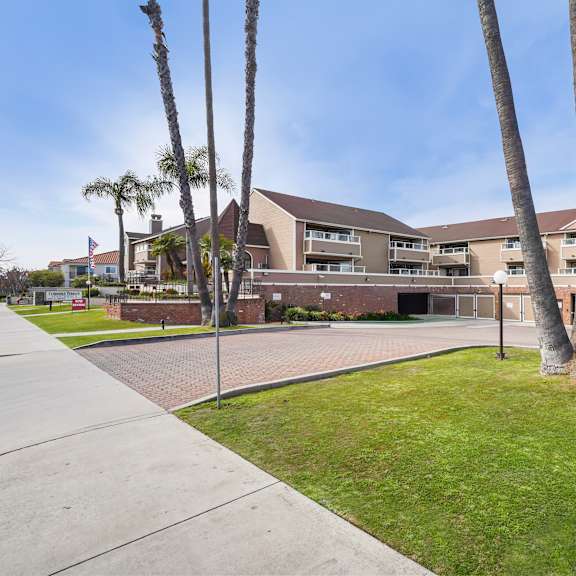 a building with a flag on the left and a palm tree in front.
