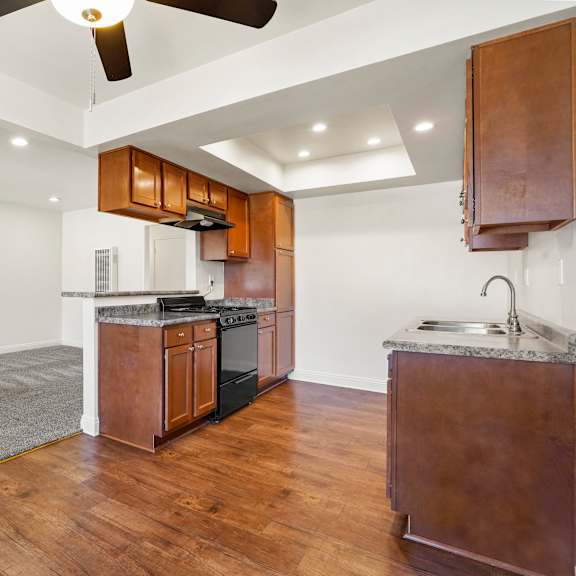a kitchen with wooden cabinets and a white ceiling fan.